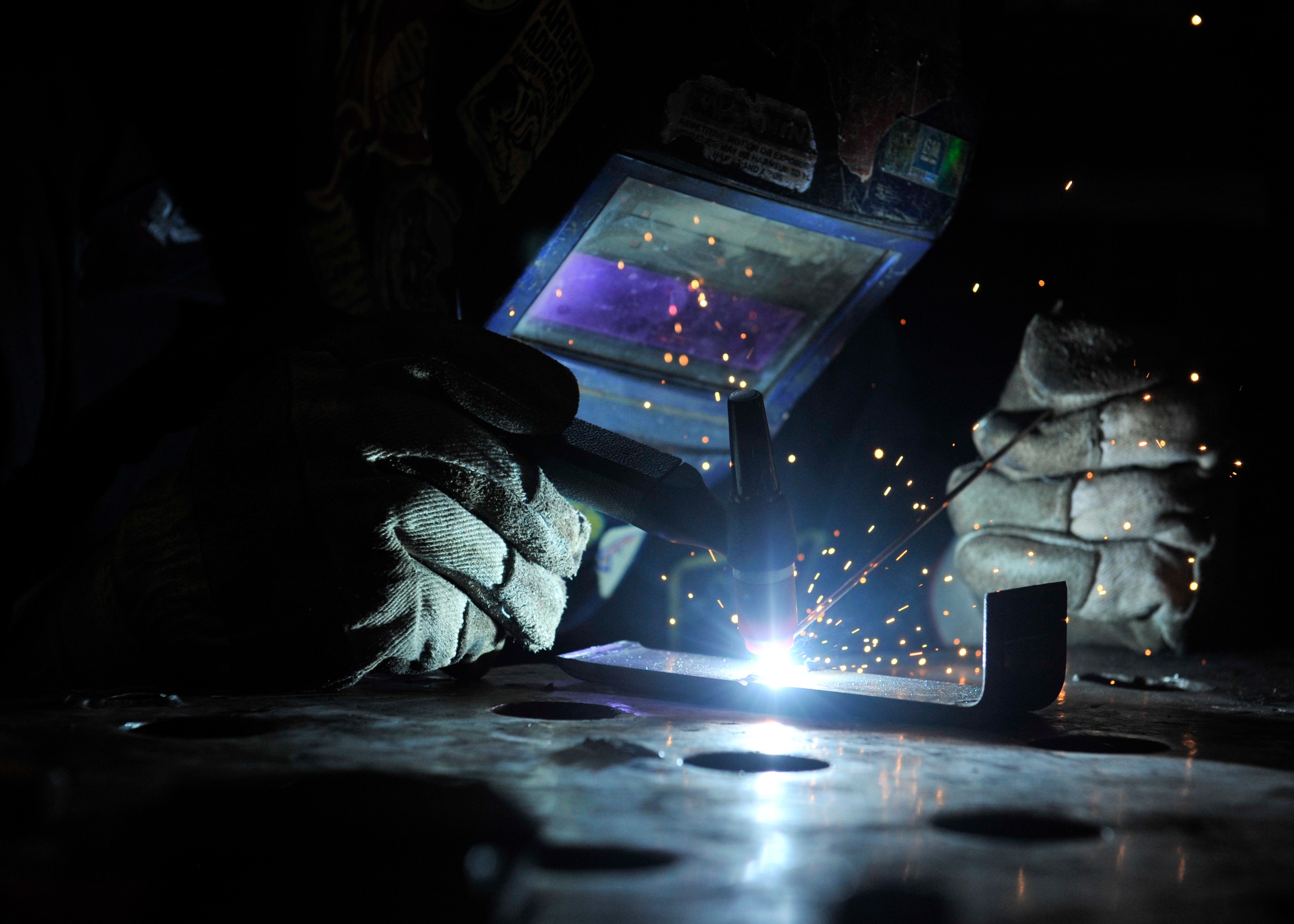 Close macro of a sailor welding aboard the USS Nimitz, rod and arc in tight focus